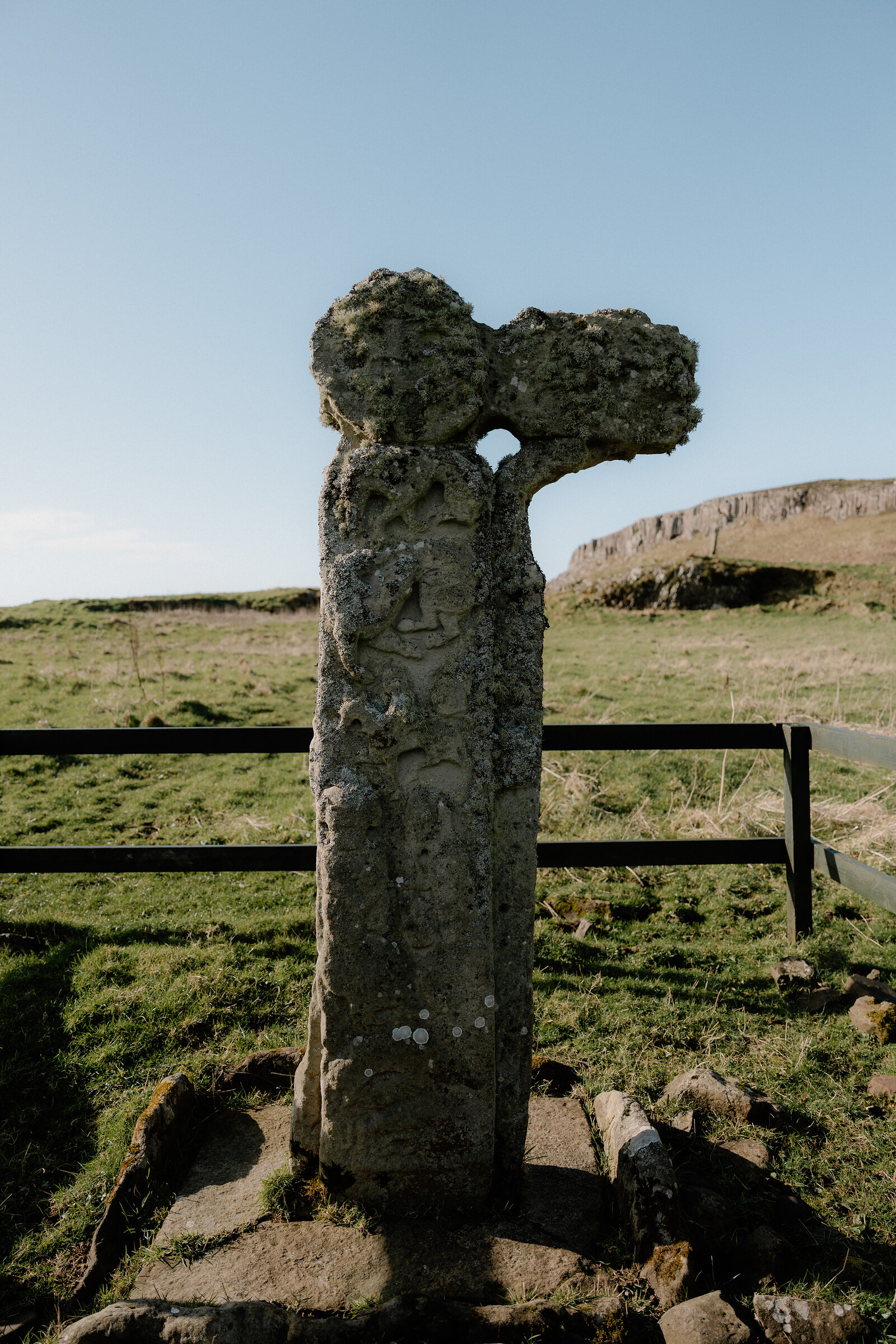 The carved wheel-head of the Isle of Canna's early Christian cross rises above a protective fence.