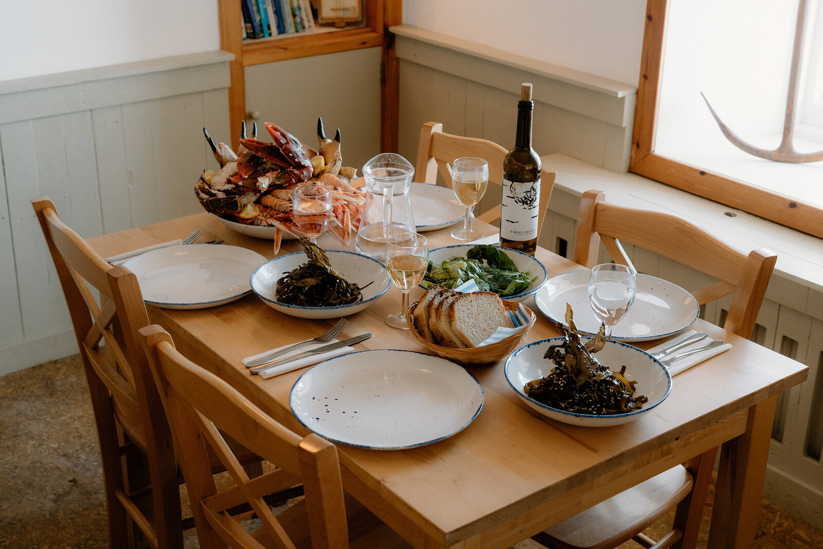 A table set with a platter of shellfish, seaweed, bread and wine in Café Canna's dining room.