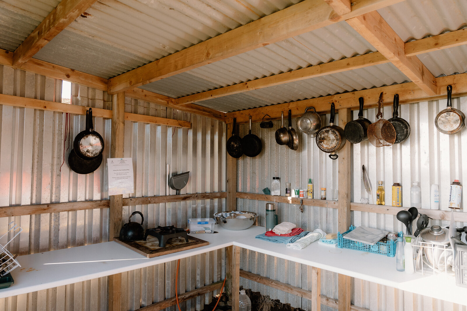 Pots and pans hang above a worktop inside a corrugated-iron kitchen shed on the Isle of Canna.