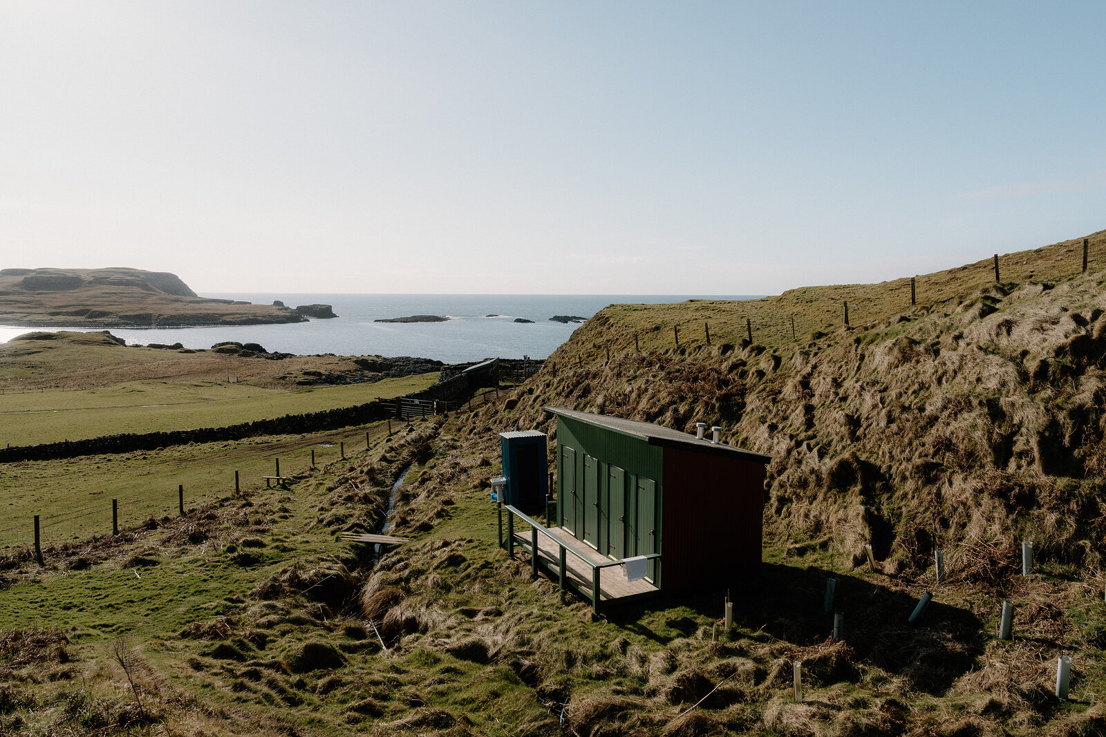 A dark timber cabin overlooks a bay dotted with small islands on the Isle of Canna.