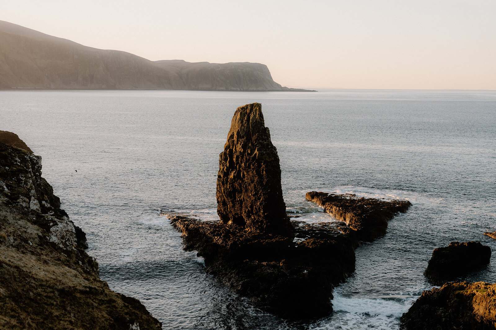 A sea stack off Sanday's south coast, the waves breaking round its foot.