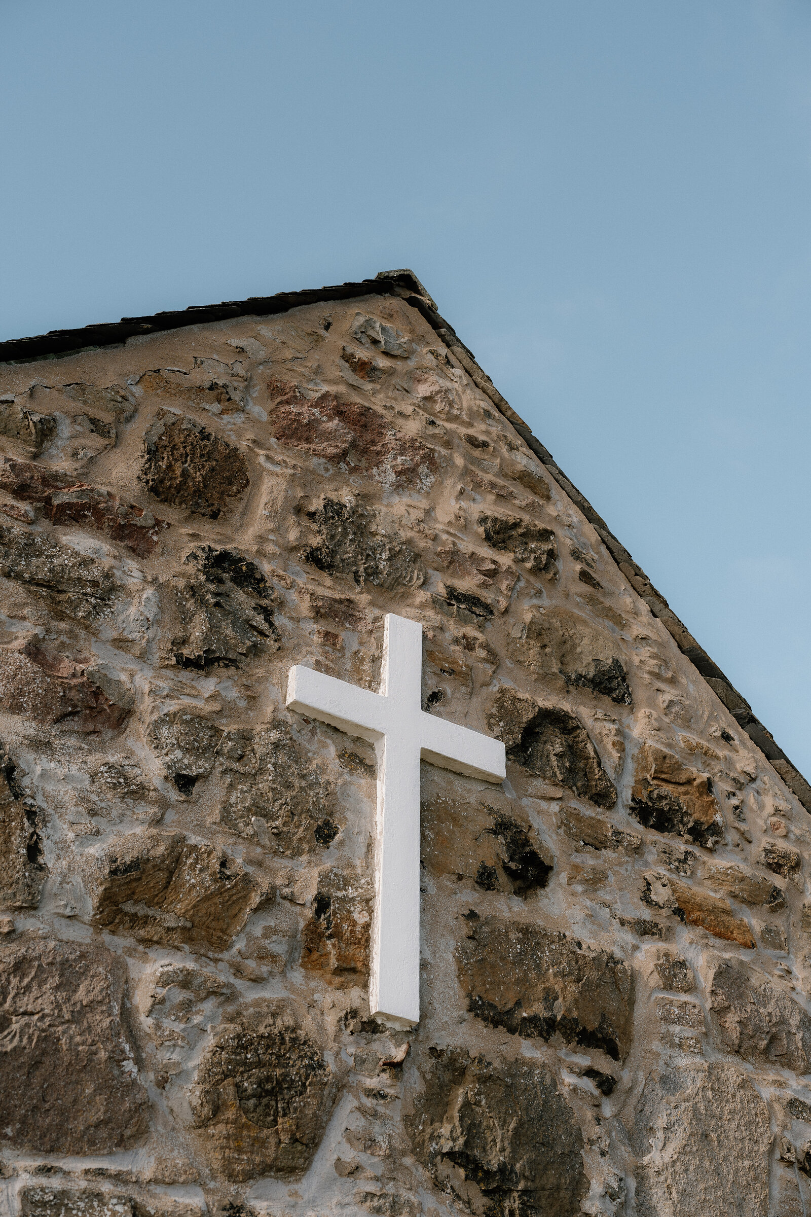 A white cross is mounted on the stone gable of a chapel on the Isle of Canna.