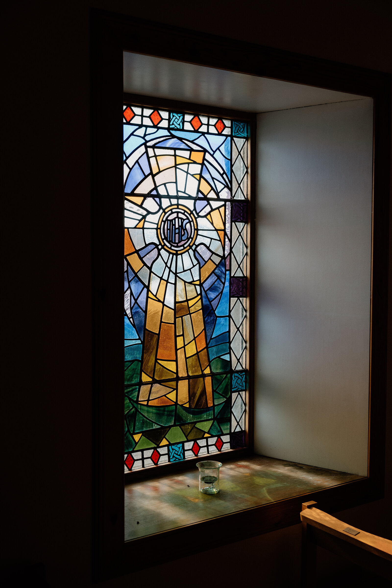 A stained-glass window depicting a robed figure lights a small alcove on the Isle of Canna.