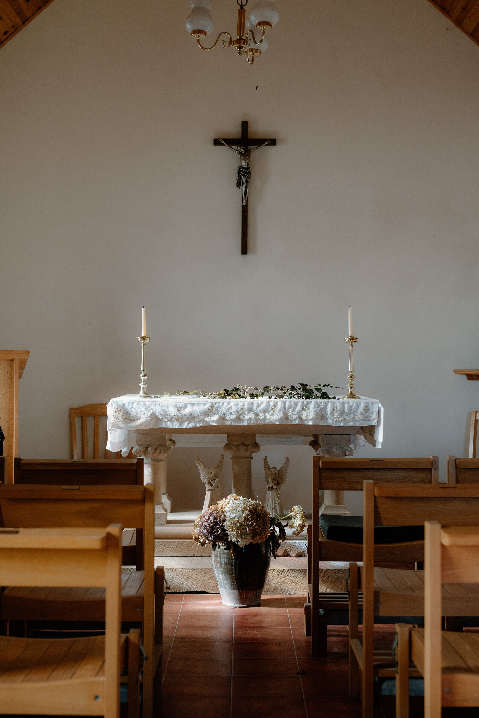 Wooden pews face a crucifix and flower-decked altar in a chapel on the Isle of Canna.