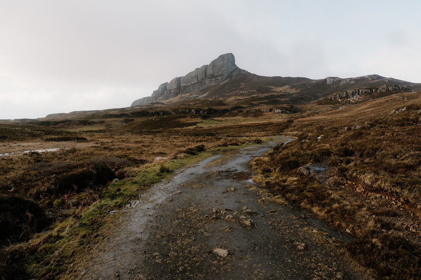 A stony path leading across moorland towards a jagged rocky ridge