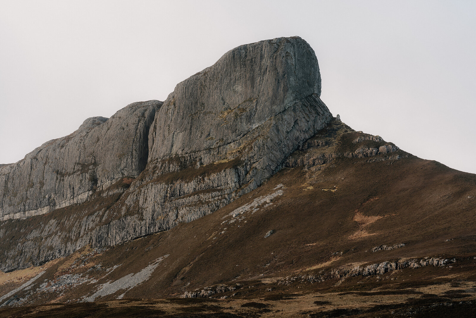 A jagged rocky summit rising above heather-covered moorland