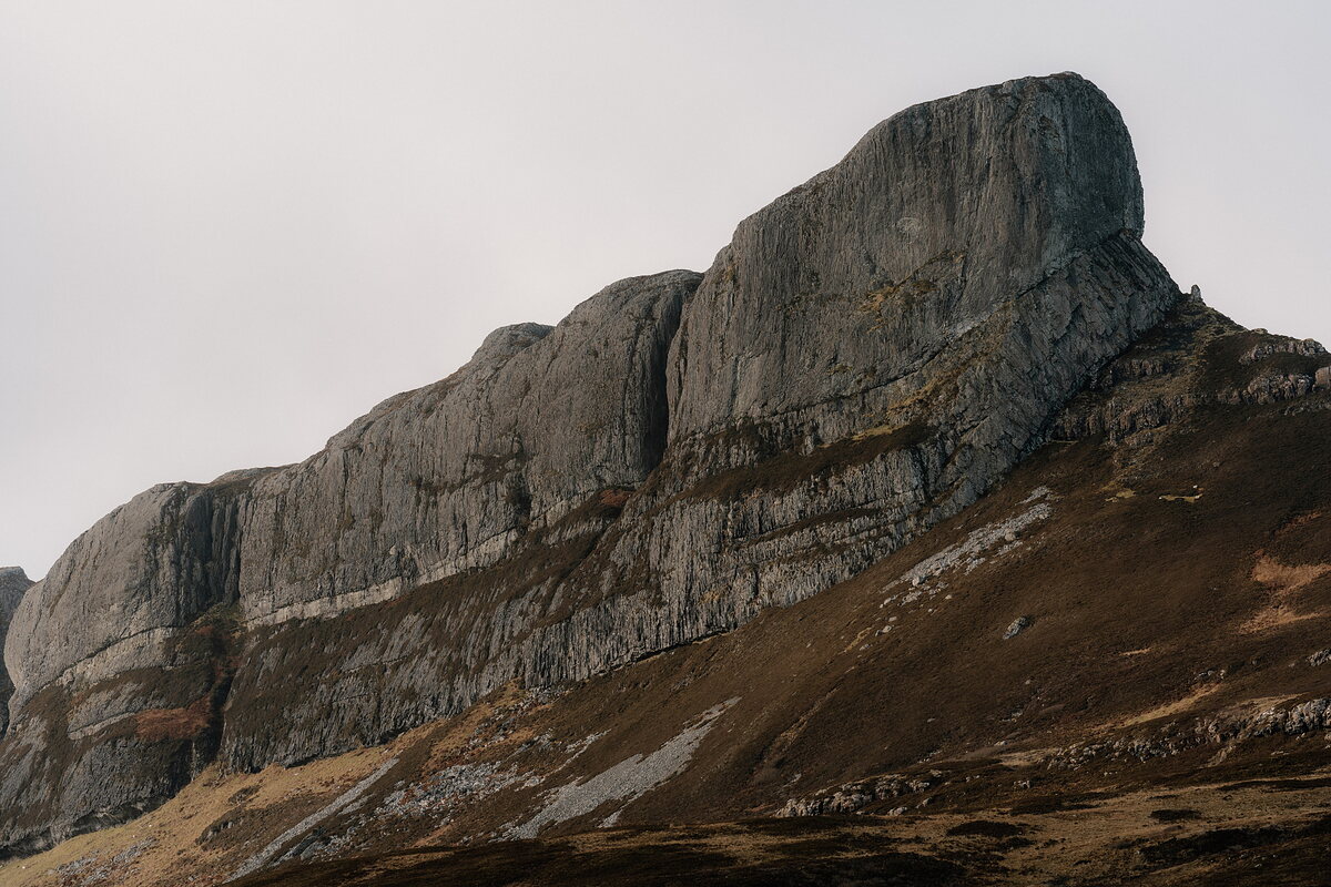 A jagged rocky ridge rising above moorland, its cliffs streaked with scree.