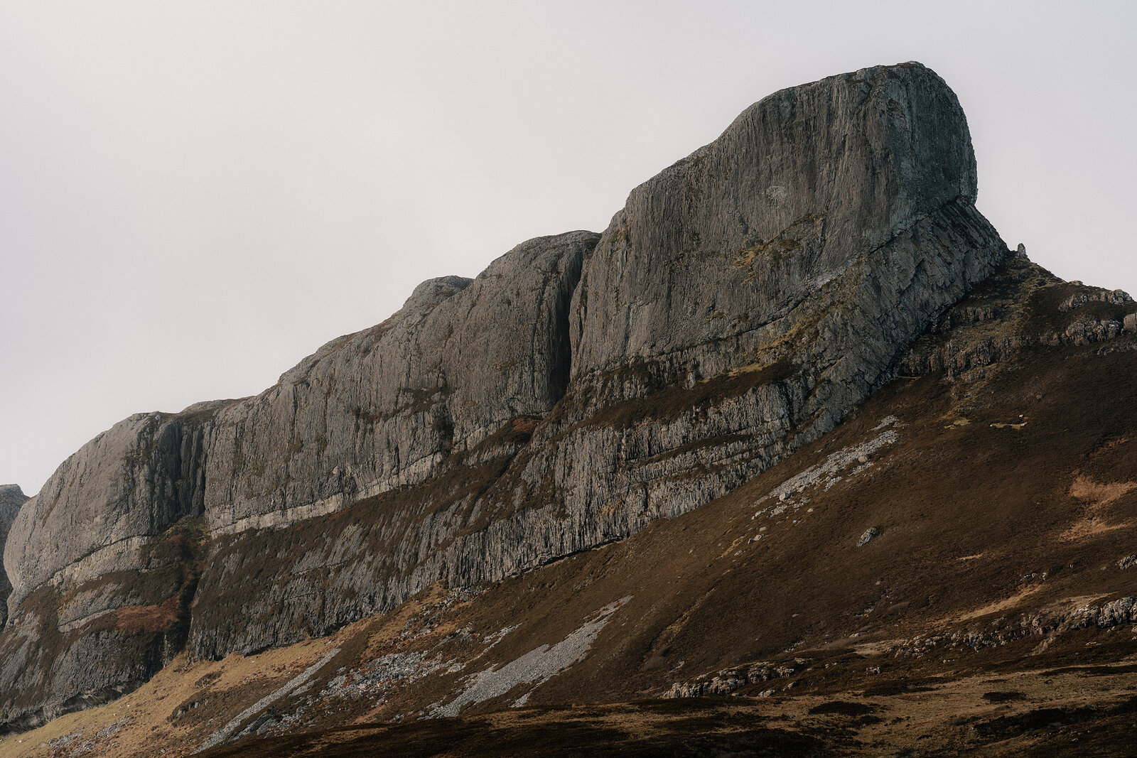A jagged rocky ridge rising above moorland, its cliffs streaked with scree