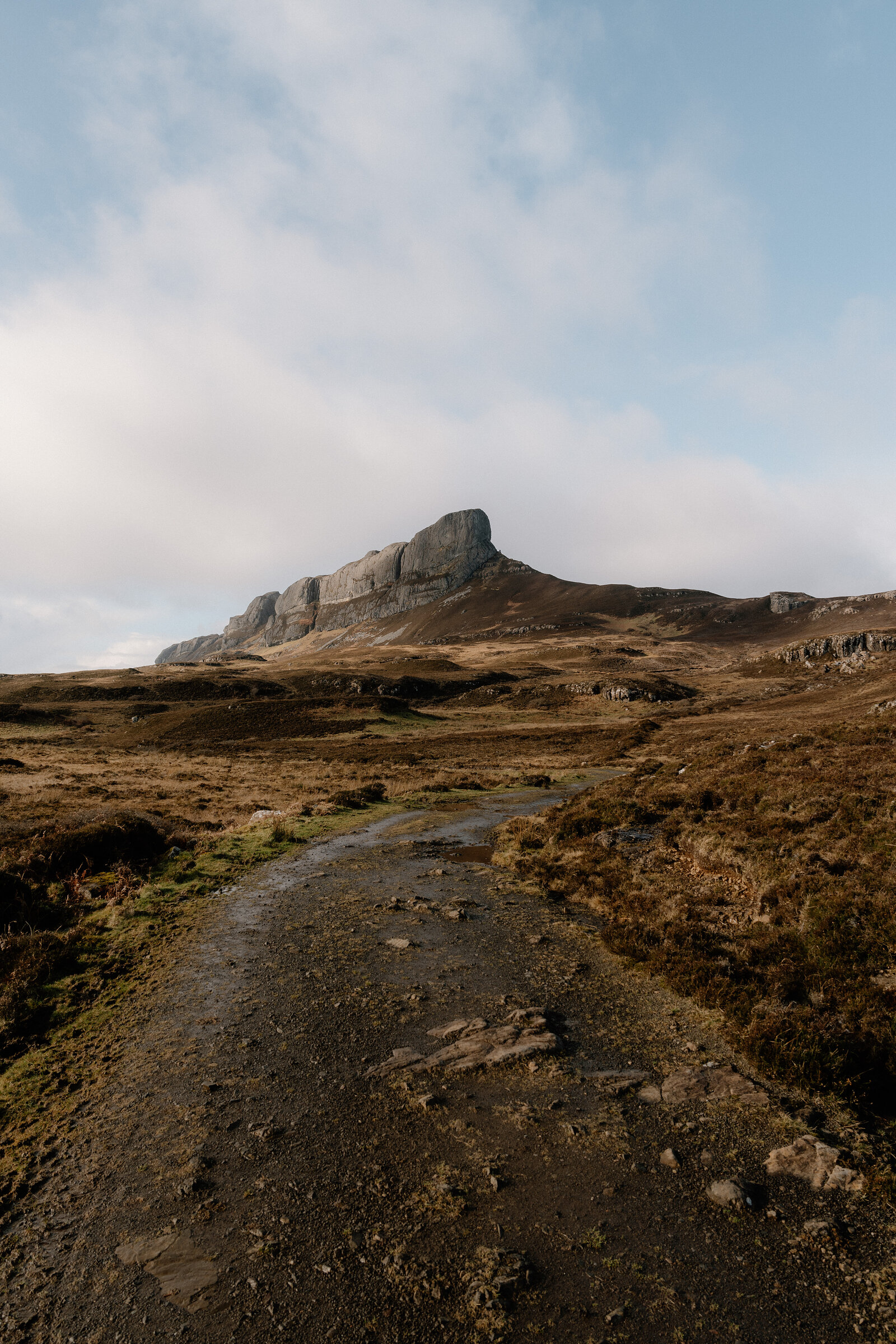 A stony track leading towards a jagged rocky peak across moorland