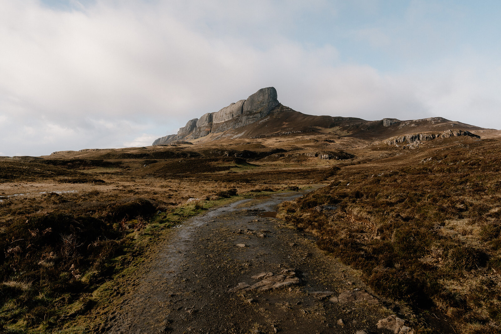 A gravel path leading towards a jagged rocky peak across moorland