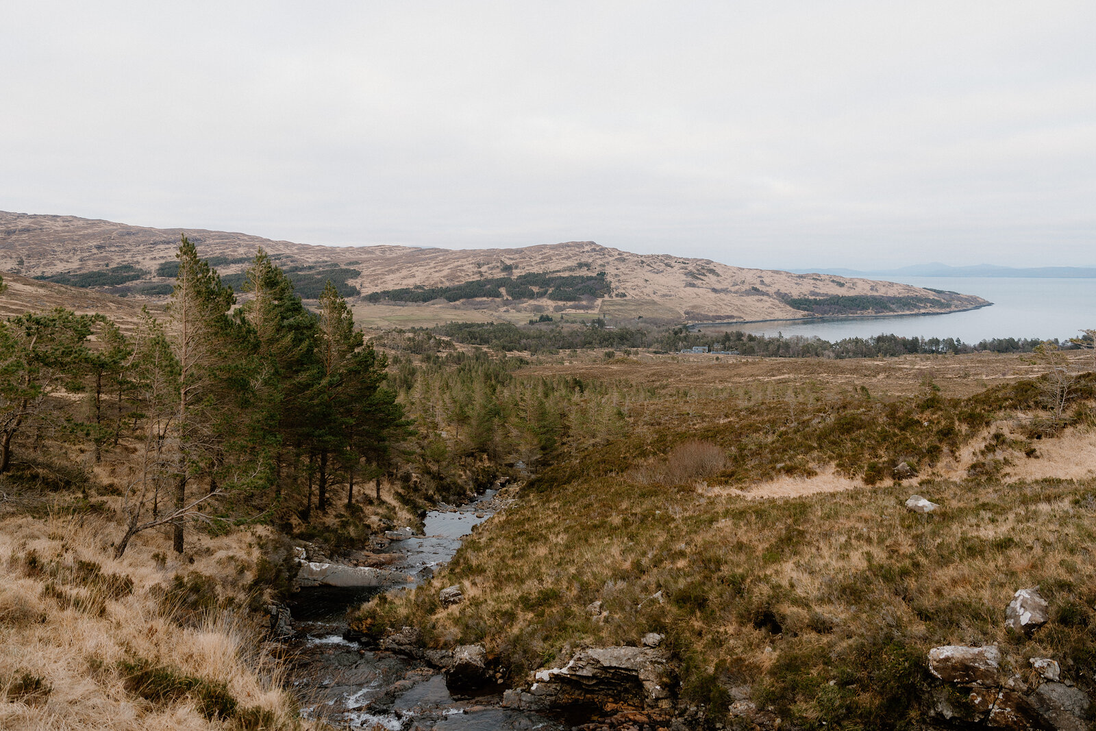 A burn winds through moorland toward a distant sea loch on the Isle of Rum.