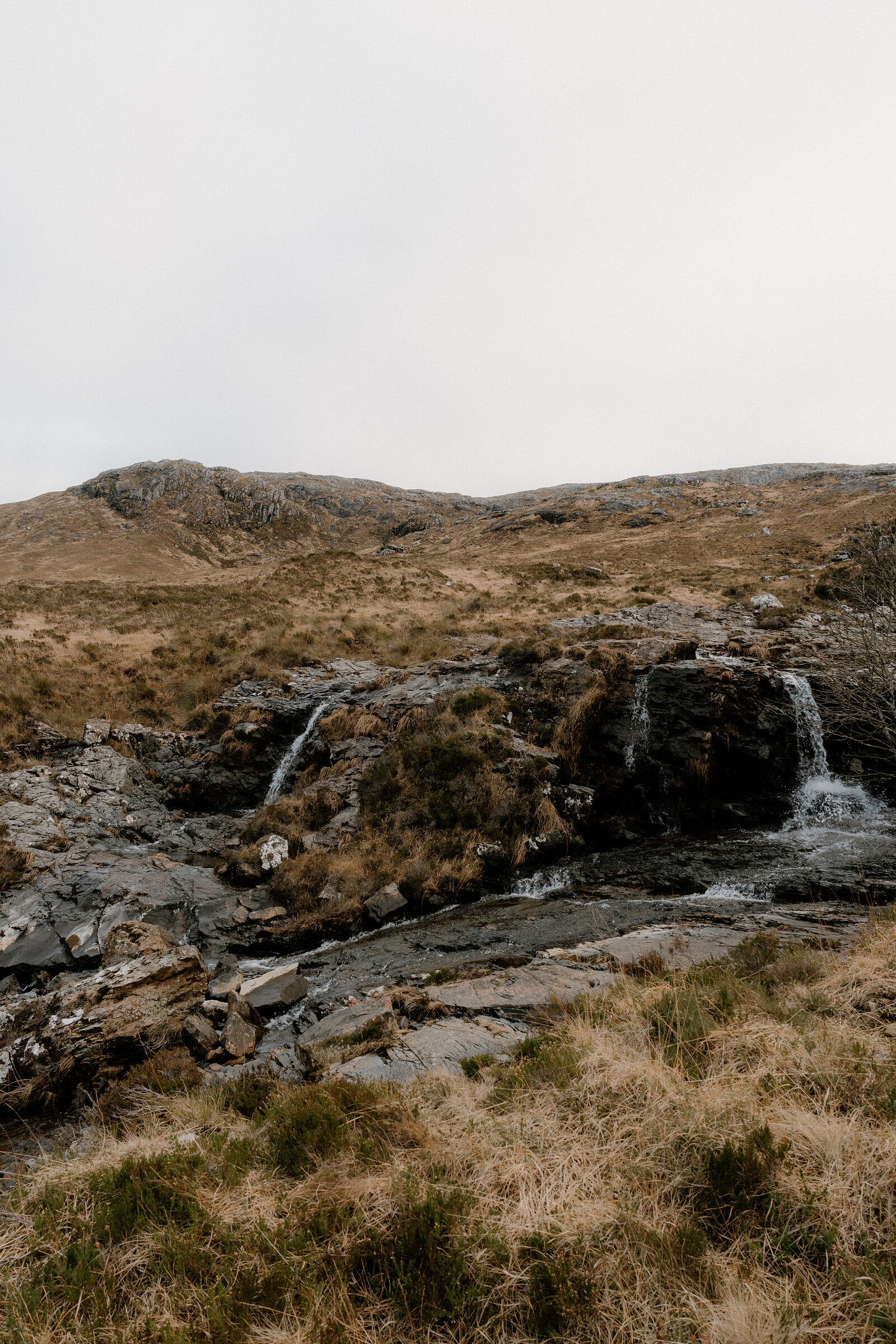 A burn cascades through a rocky cleft on moorland on the Isle of Rum.