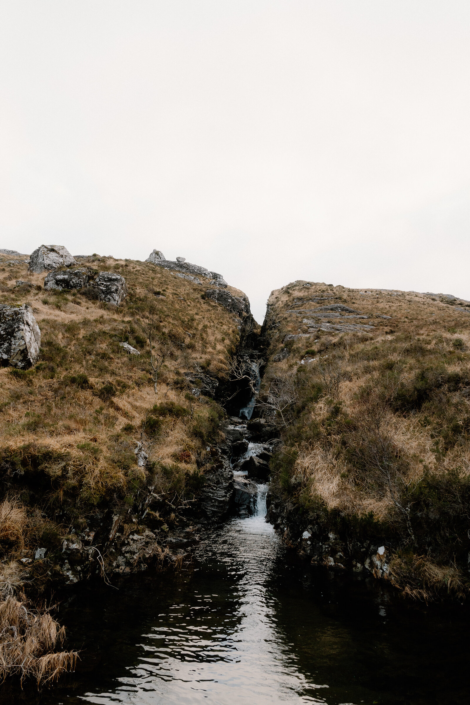 A narrow burn drops through a mossy rock cleft on the Isle of Rum.