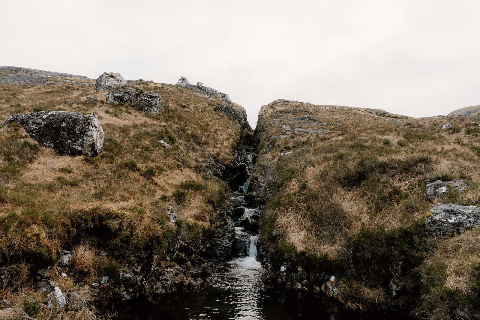 Water trickles through a narrow rocky gully on moorland on the Isle of Rum.