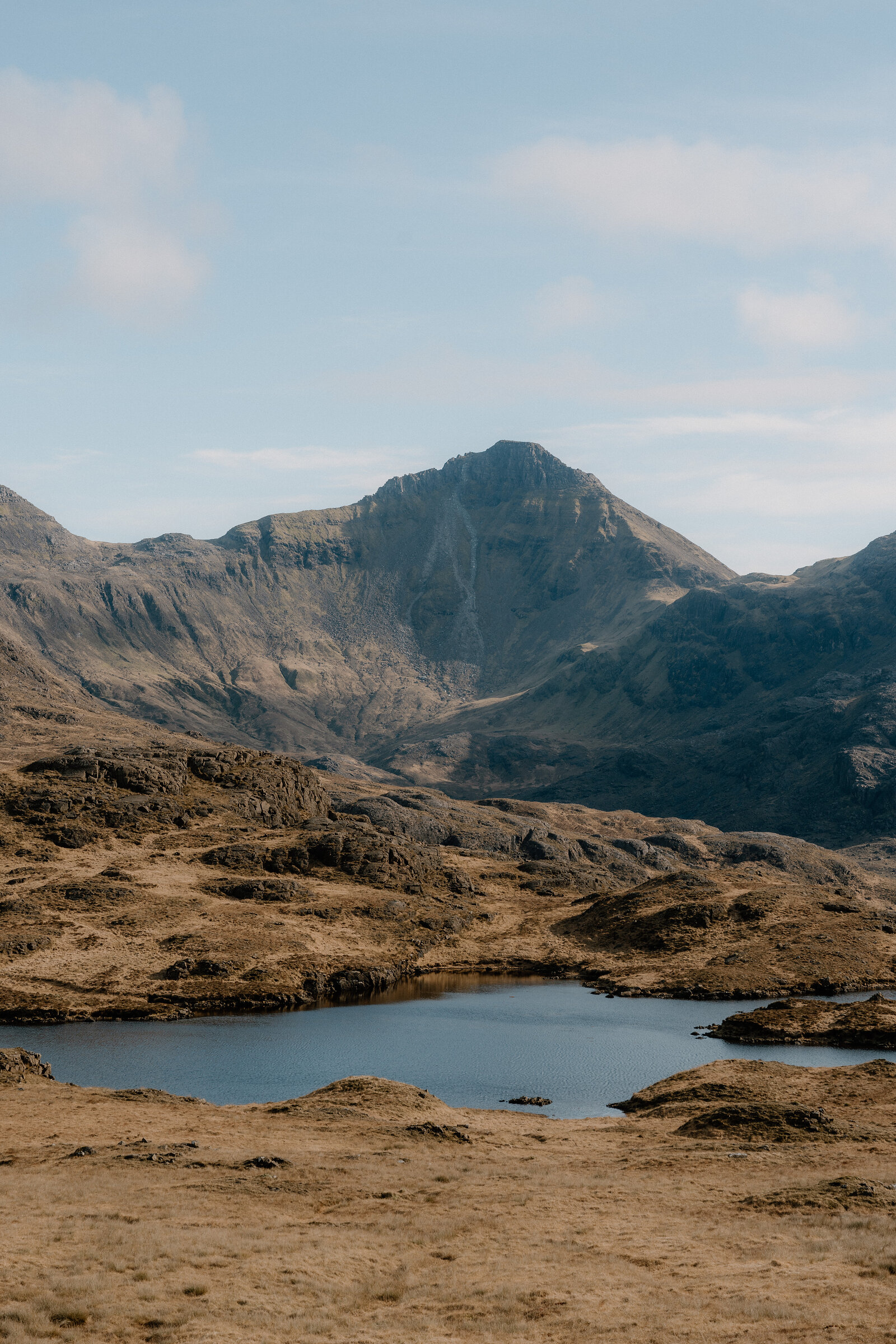 A small loch sits beneath a jagged mountain peak on the Isle of Rum.