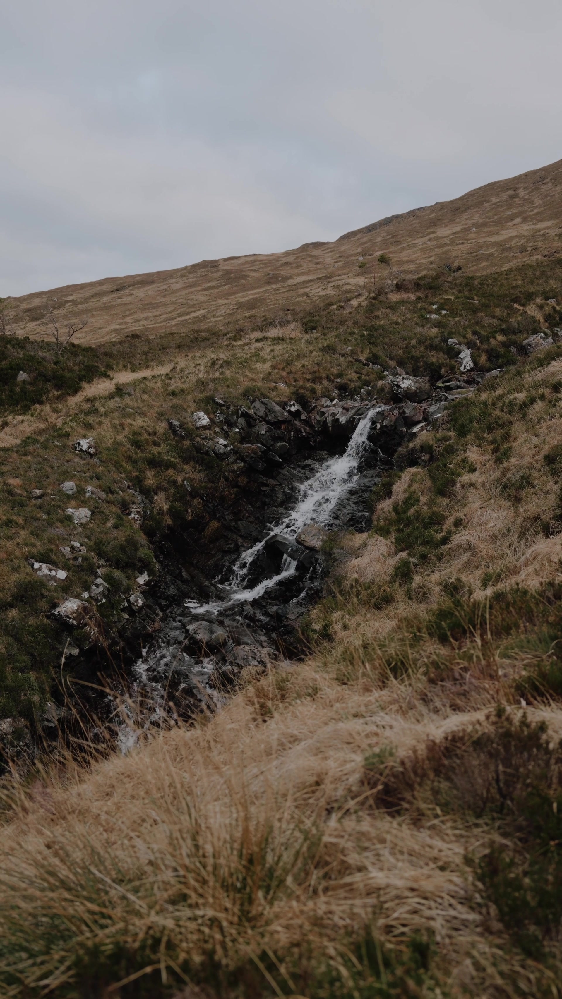 A burn tumbling down a rocky gully on open moorland on Rum
