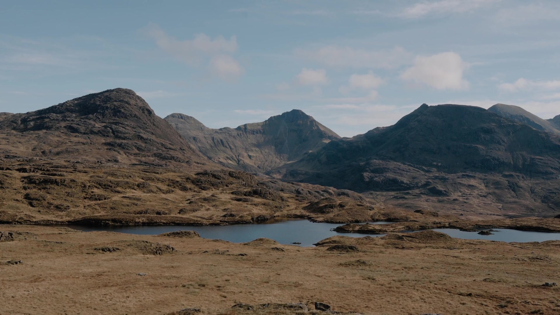 Rum's rugged mountain peaks rising above a small loch set in open moorland