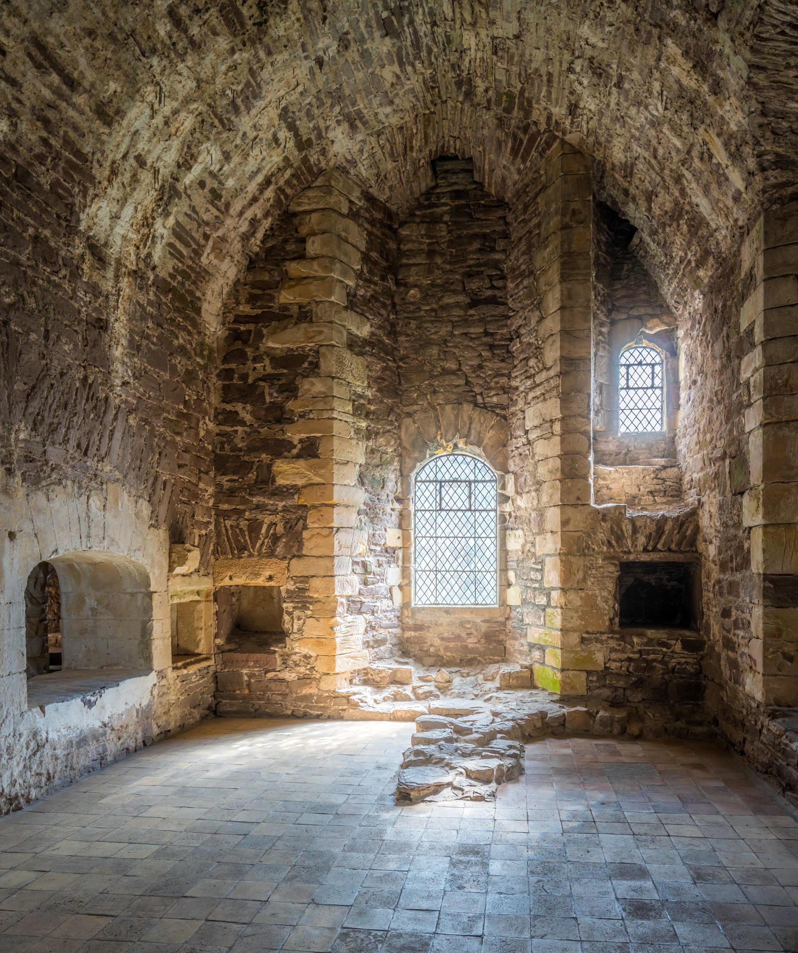 A stone-vaulted room inside Doune Castle, sunlight from a small leaded window falling across the flagged floor.