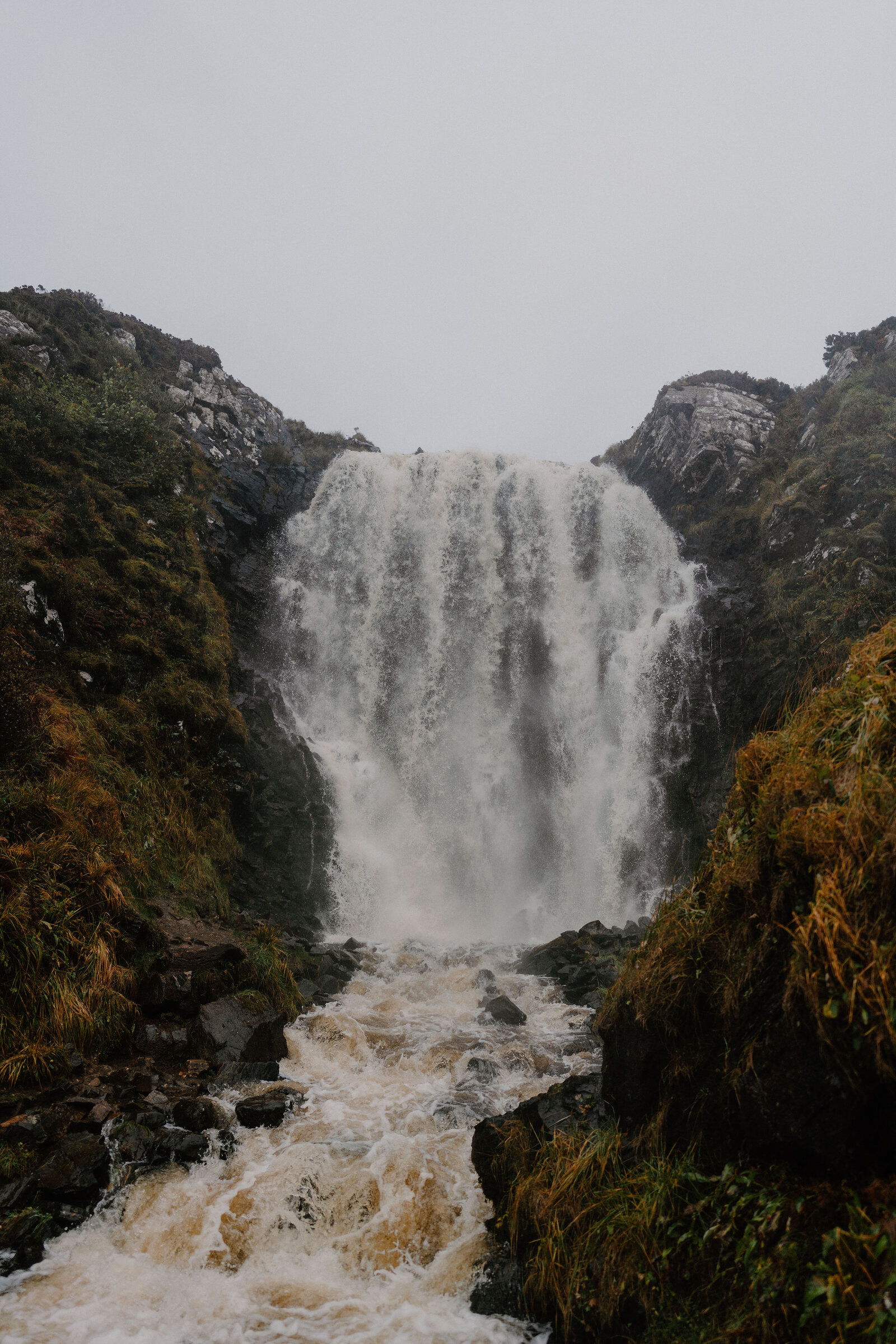 A waterfall crashing down a rocky gorge, mist rising from the churning pool below