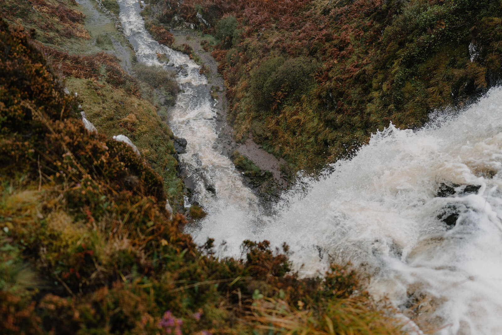 A waterfall splitting into channels as it tumbles through heather-covered rocks