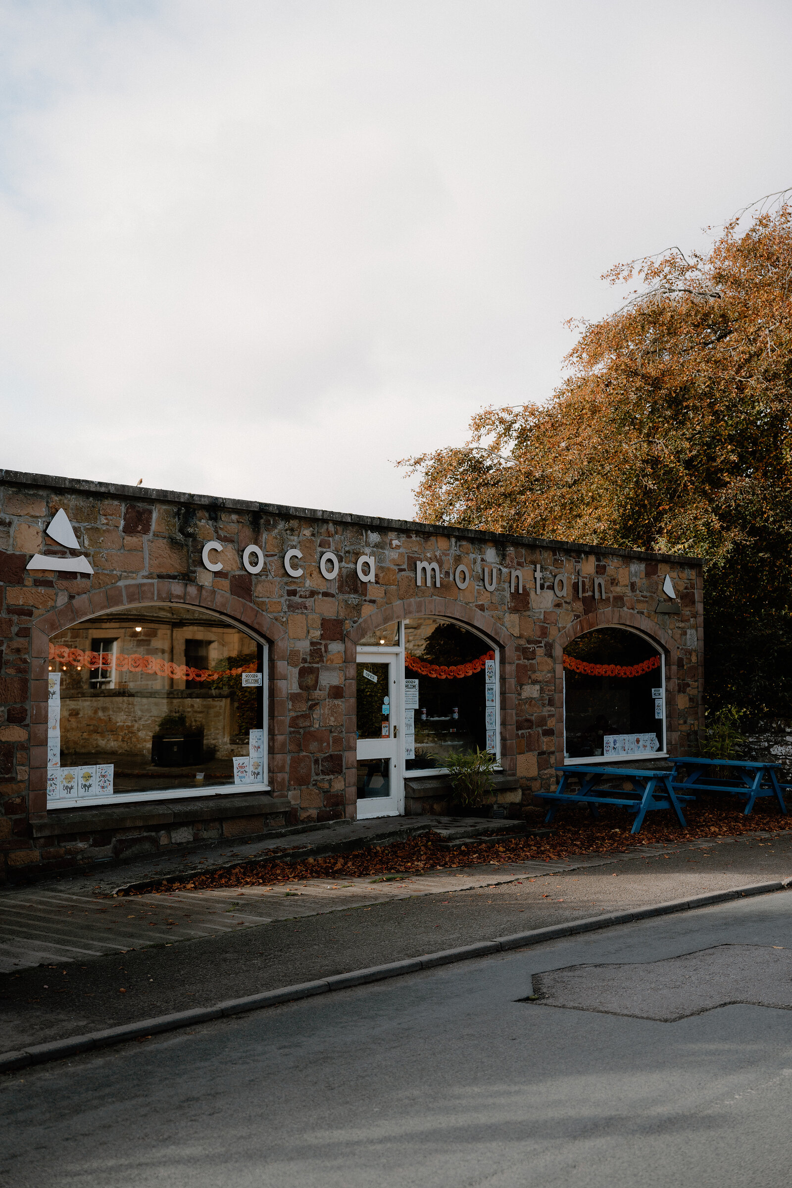 Cocoa Mountain's arched stone frontage opens beside a blue picnic table.