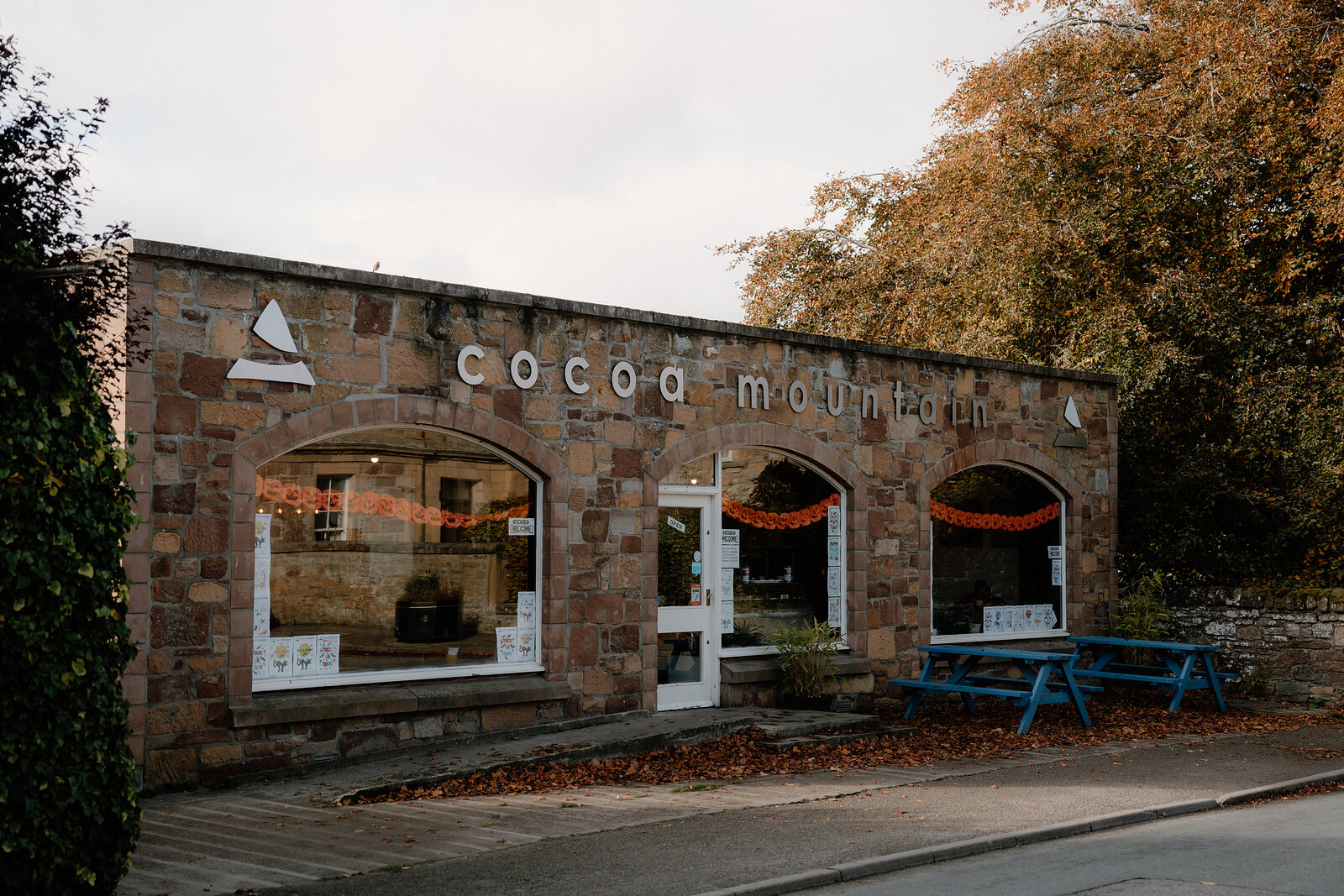 Cocoa Mountain's arched stone shopfront stands beside an empty street and picnic table.