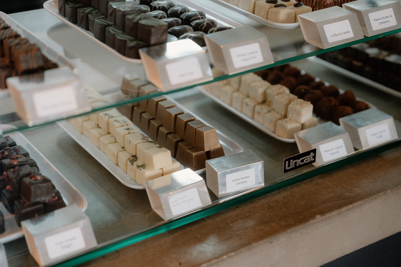 Rows of chocolate truffles and pralines fill a glass display case.