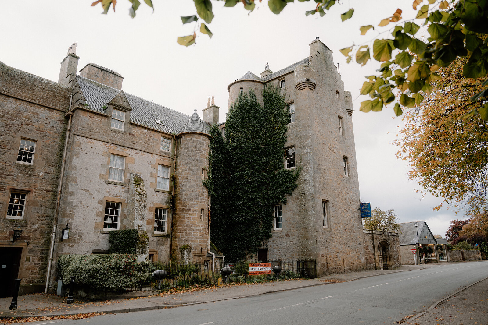 Ivy wraps a turreted hotel tower beside a quiet street.