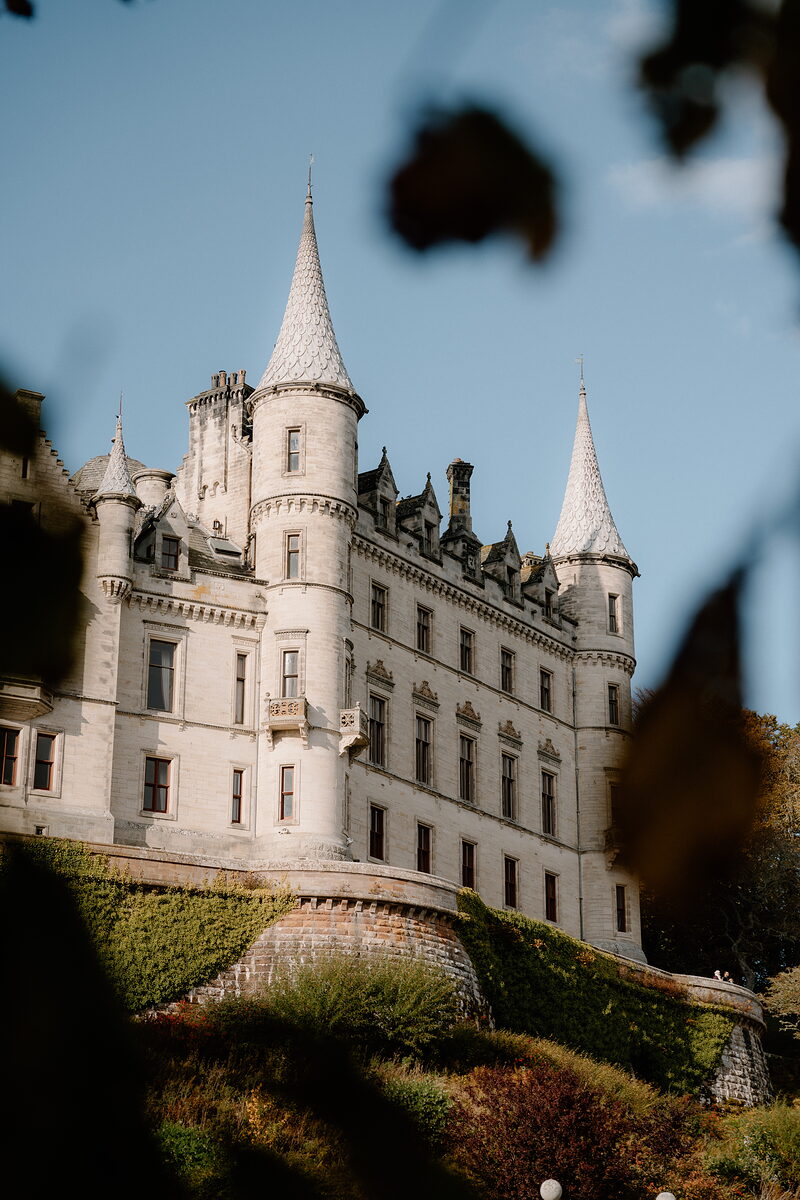 Autumn leaves frame a turreted white castle rising above its grounds.