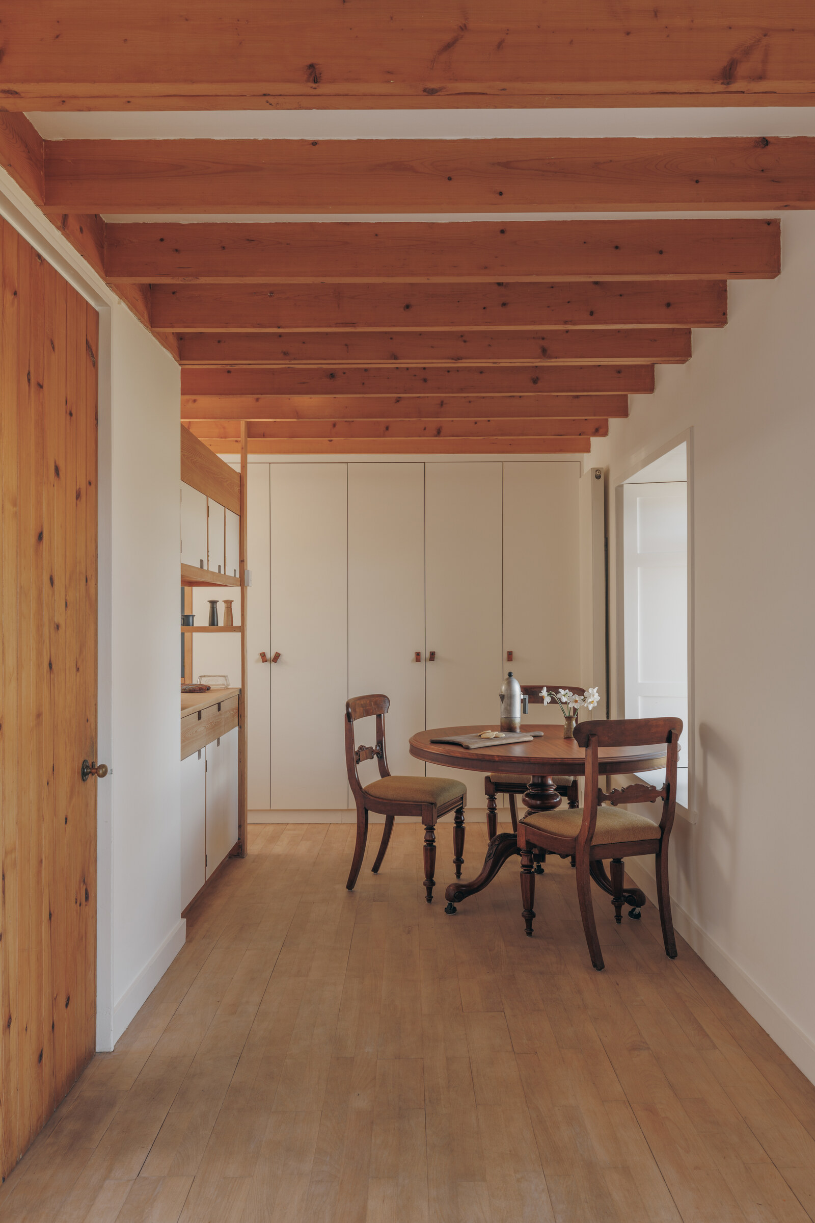 A round table and chairs under the wooden ceiling beams in Rhuroin’s dining area.