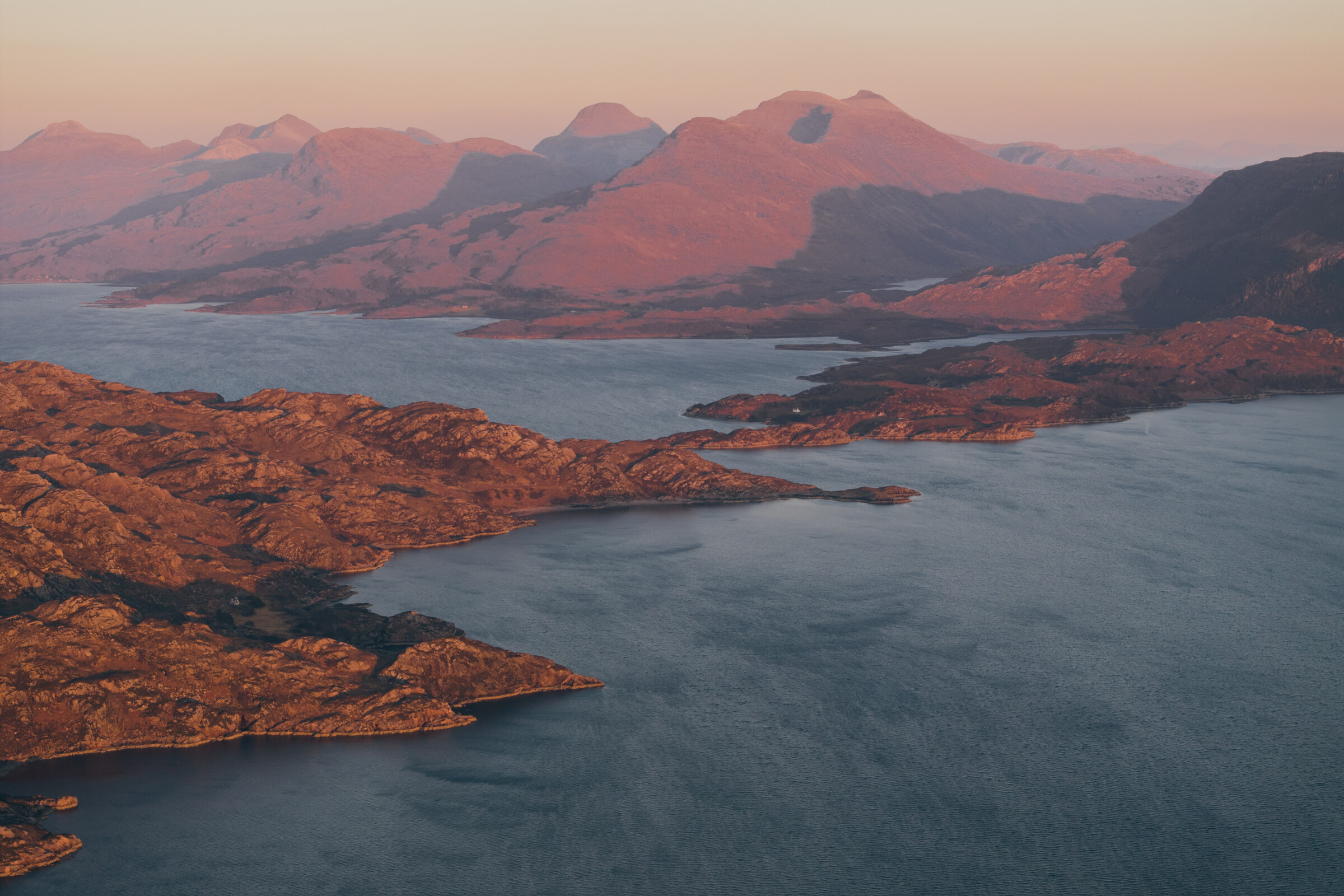The Torridon mountains catch the first pink light above the sea lochs and islands below.