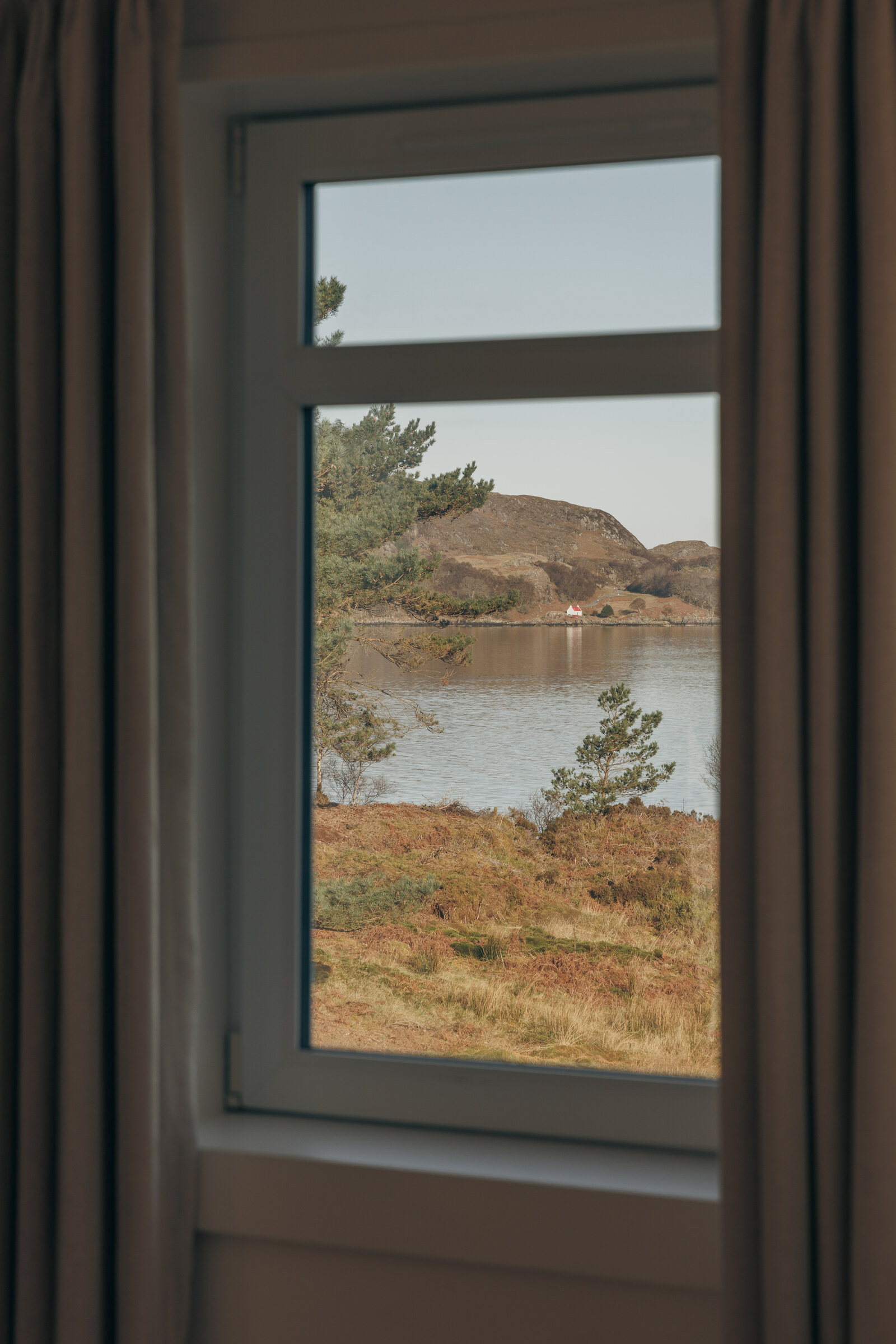 A deep-set window at Rhuroin frames the loch and a wooded island beyond.