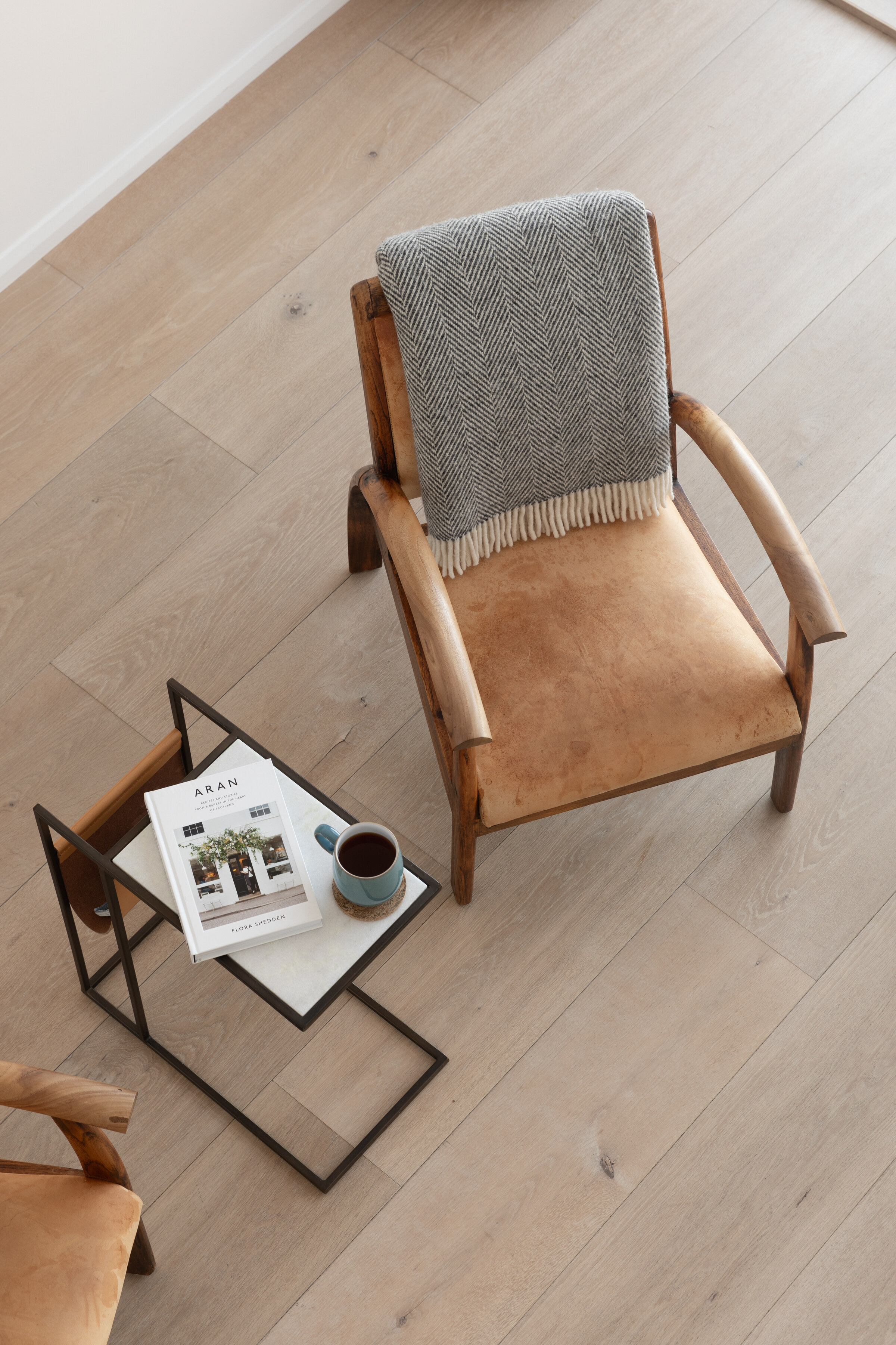 A tan leather armchair with a grey throw beside a small glass side table, seen from above.