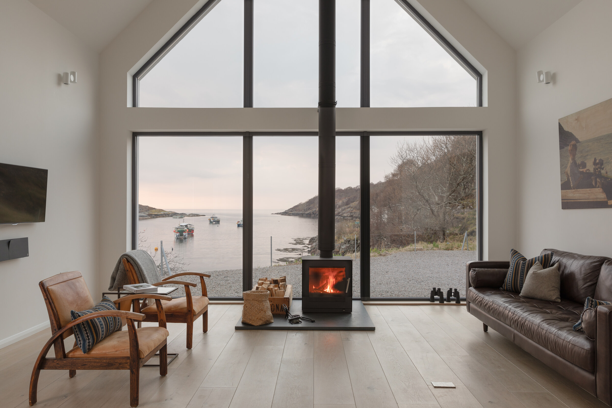 A wood-burning stove glows beneath The Net Store’s tall gable window, which looks out over the bay to the hills.