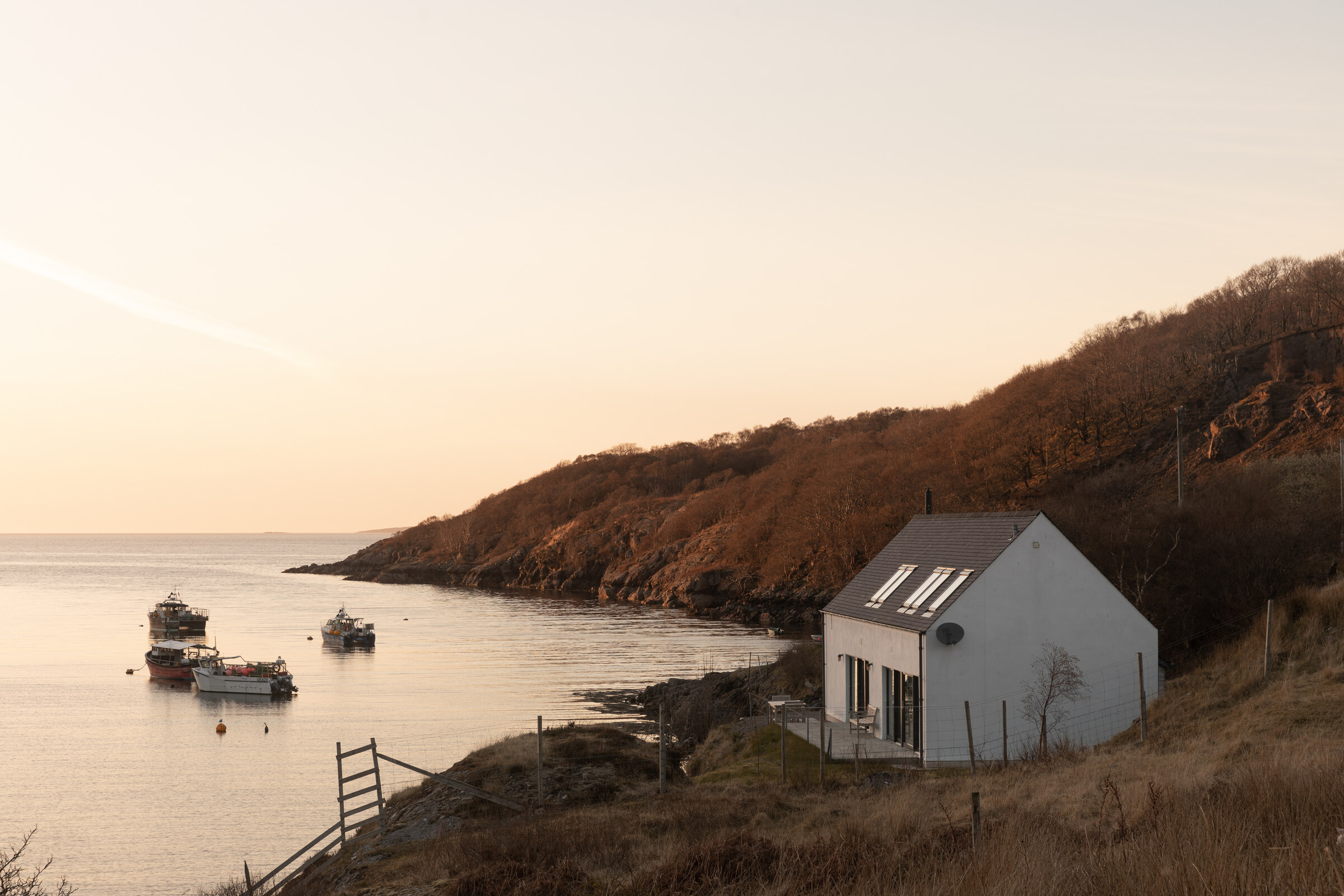 The Net Store on its rocky point at Ardheslaig, the bay and its moored boats beyond.