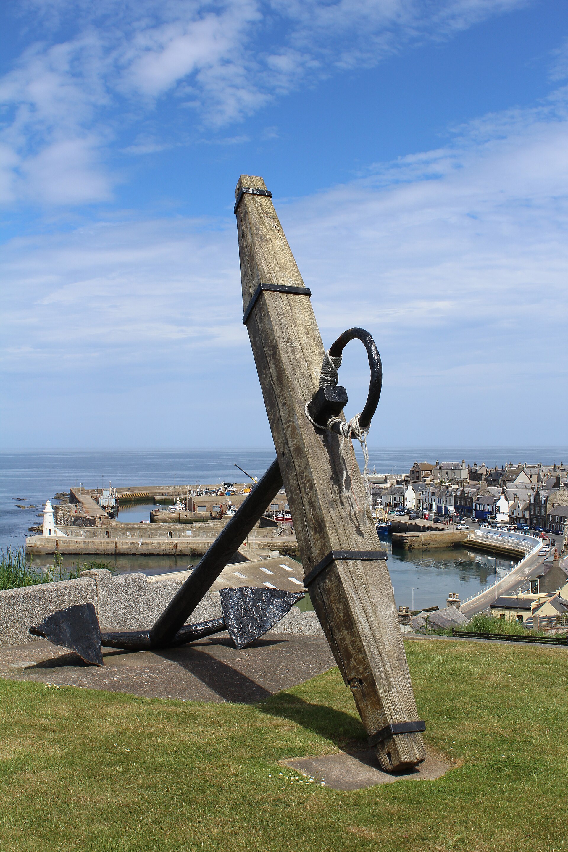 An old ship's anchor set above Macduff harbour and the sea.