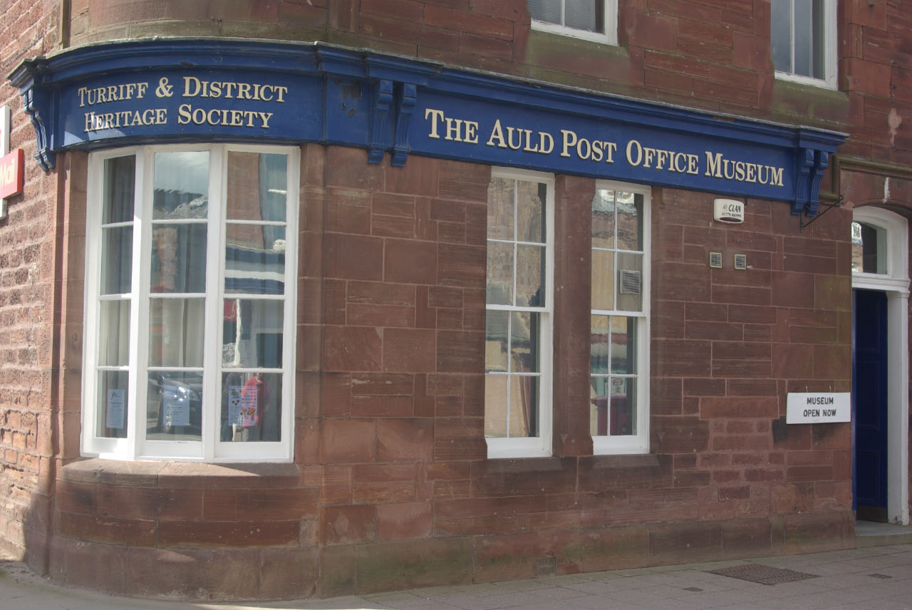 The red sandstone front of the Auld Post Office Museum in Turriff under its blue sign.