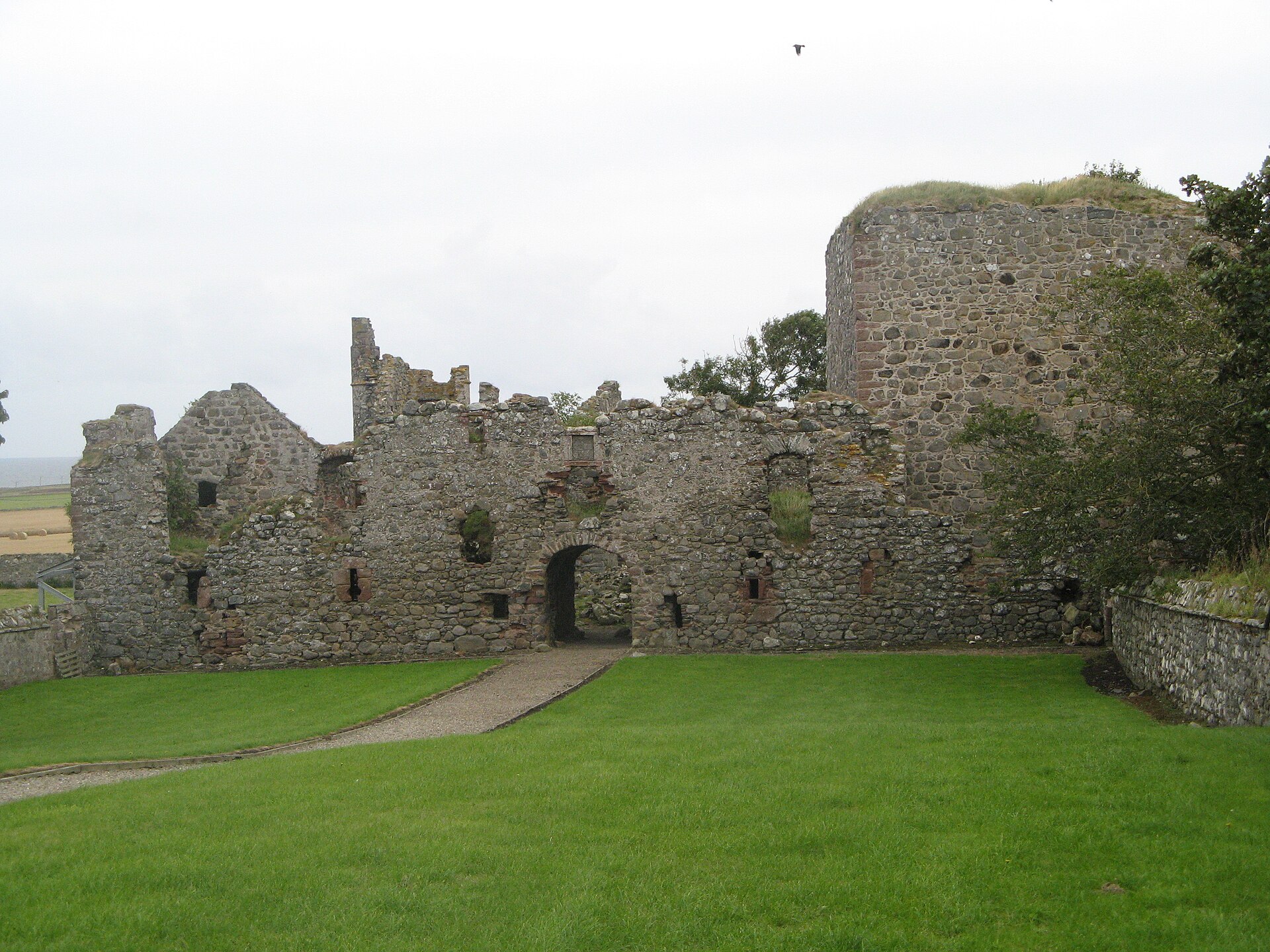 The ruined walls of Pitsligo Castle standing over a green lawn.