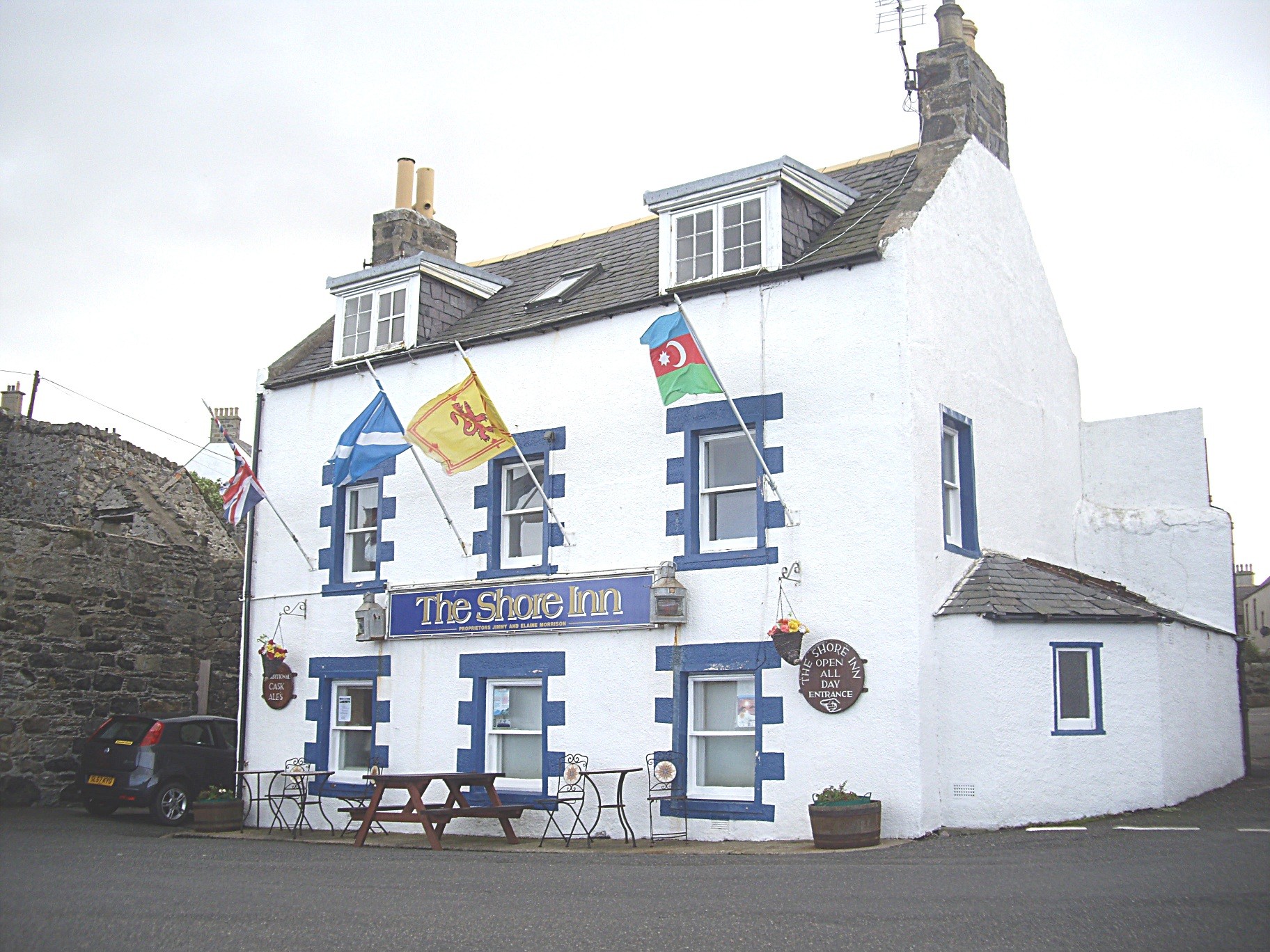 The white front of the Shore Inn on Portsoy's old harbour, flags over the door.