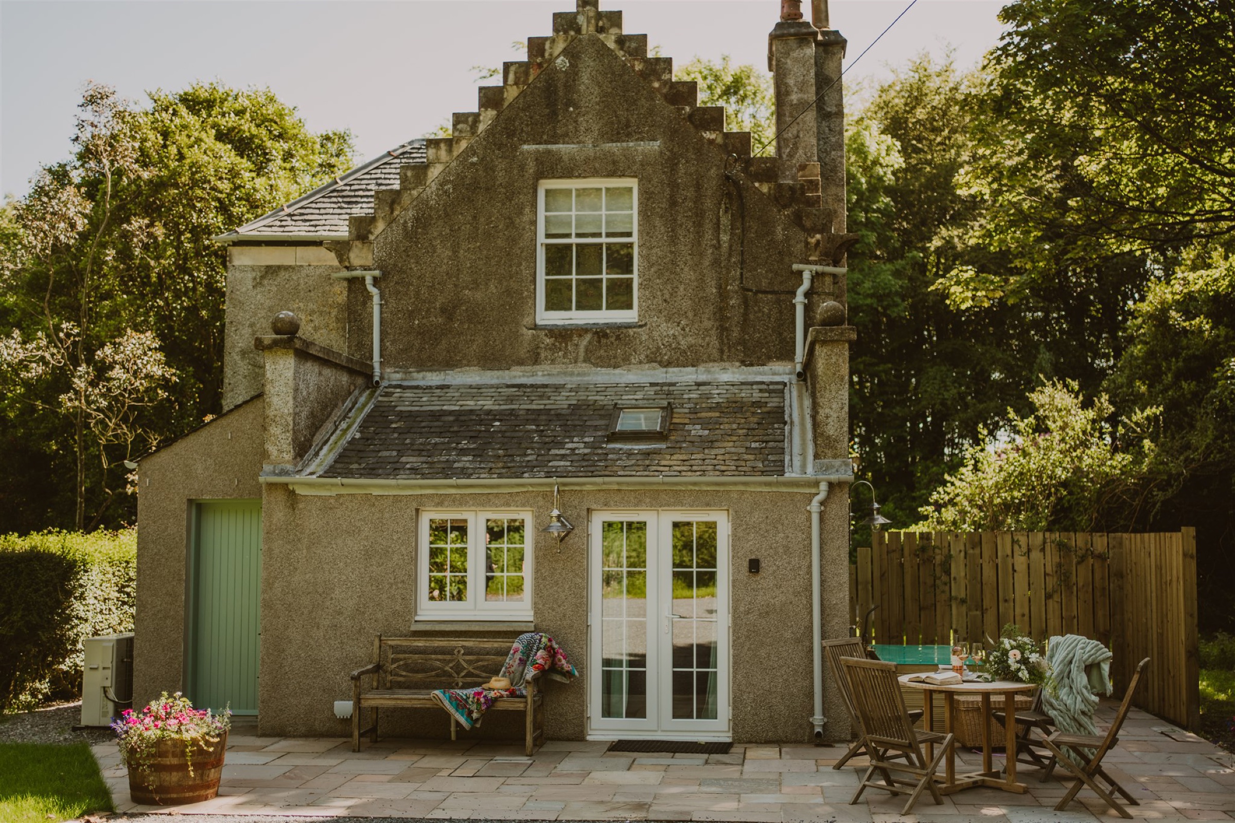 Artemisia Lodge, a stone house with a stepped gable, glazed doors onto a terrace with a bench and a table.
