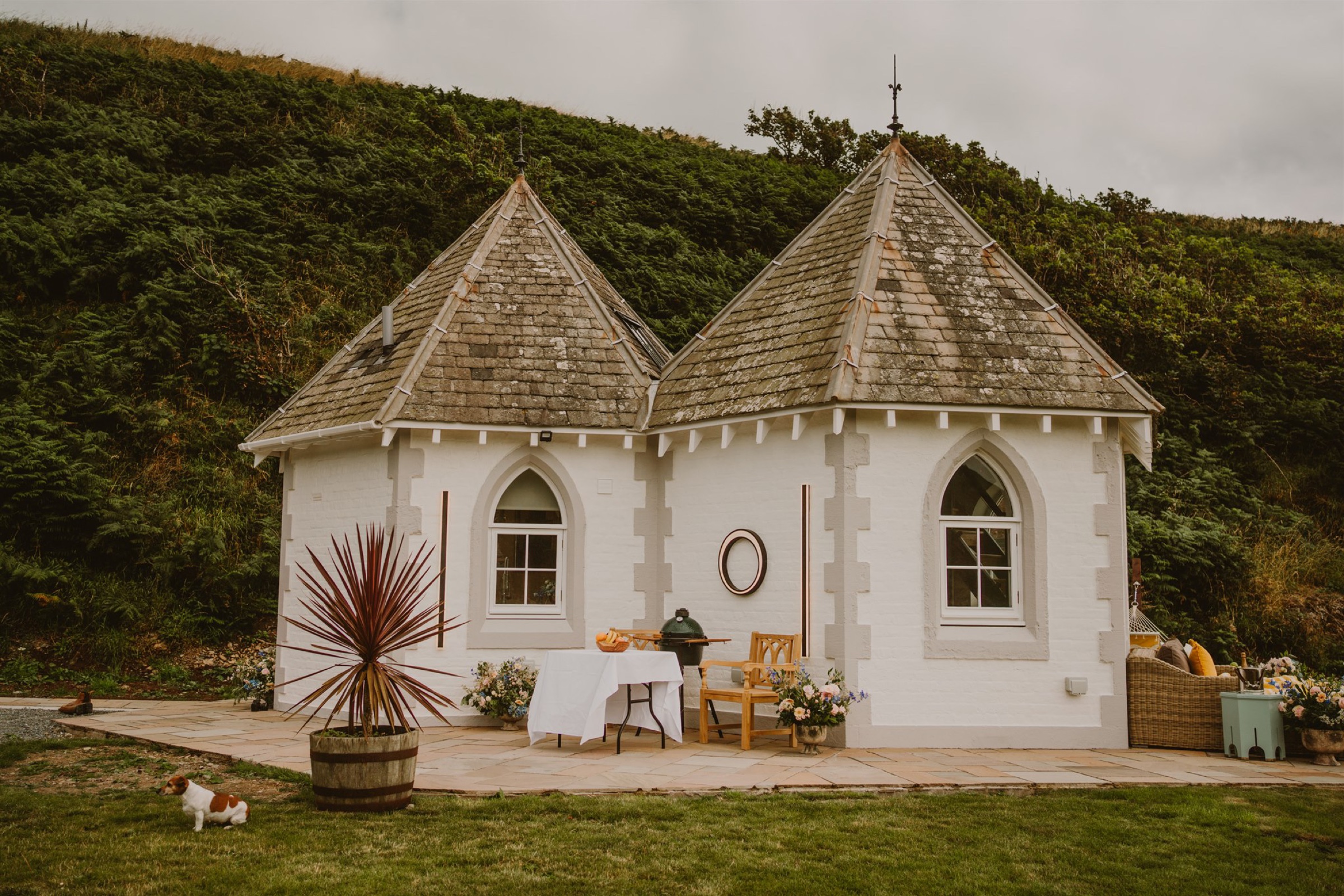 Selkie's Haven Lodge, a white building of two wings with pointed slate roofs, a table and a palm on its terrace.