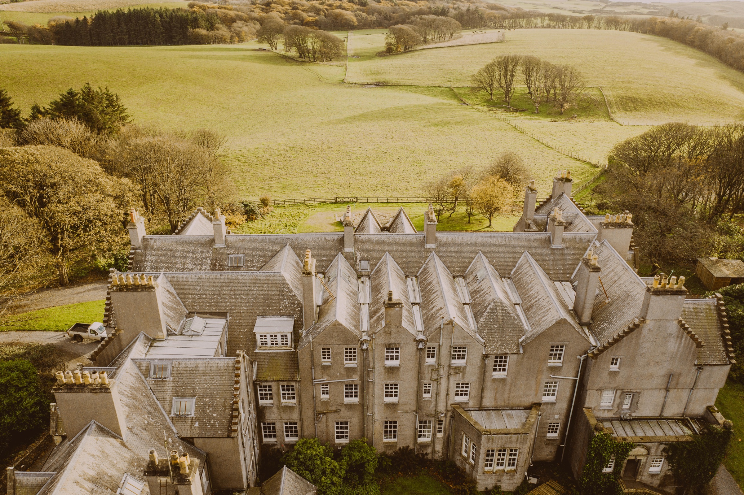 From above, Dunskey House, the castle, its grey gables and chimneys, fields and woods running to the sea behind.