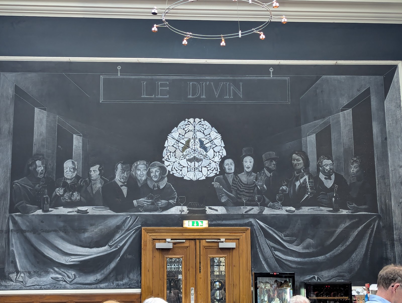 A large chalk drawing of a long dinner table across the wall of Le Di-Vin, the bar's name above it.