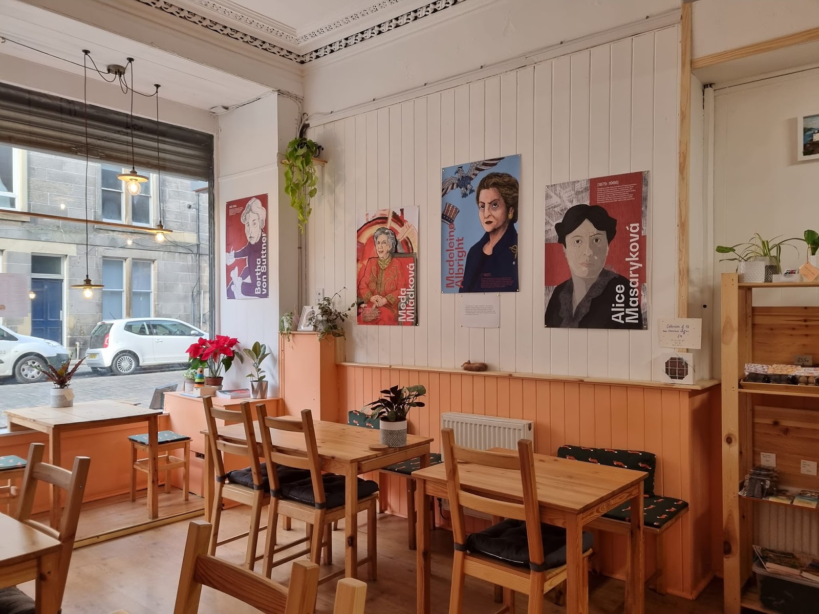The bright dining room of the Sly Fox, with wooden tables, plants and portraits on the white panelled walls.