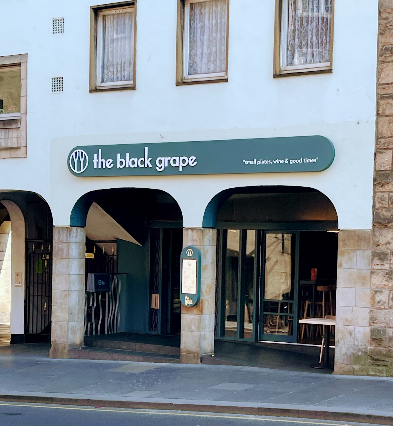 The front of the Black Grape on the Canongate, its sign over arched windows in a white building.