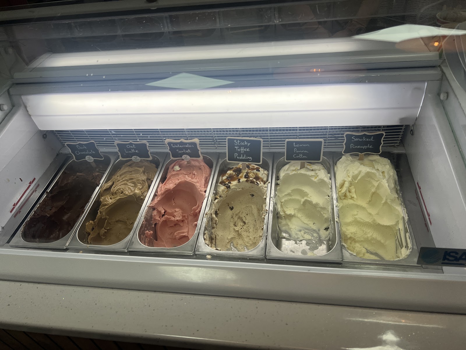 Trays of gelato in the counter at Basement Gelato, each flavour labelled on a small blackboard.