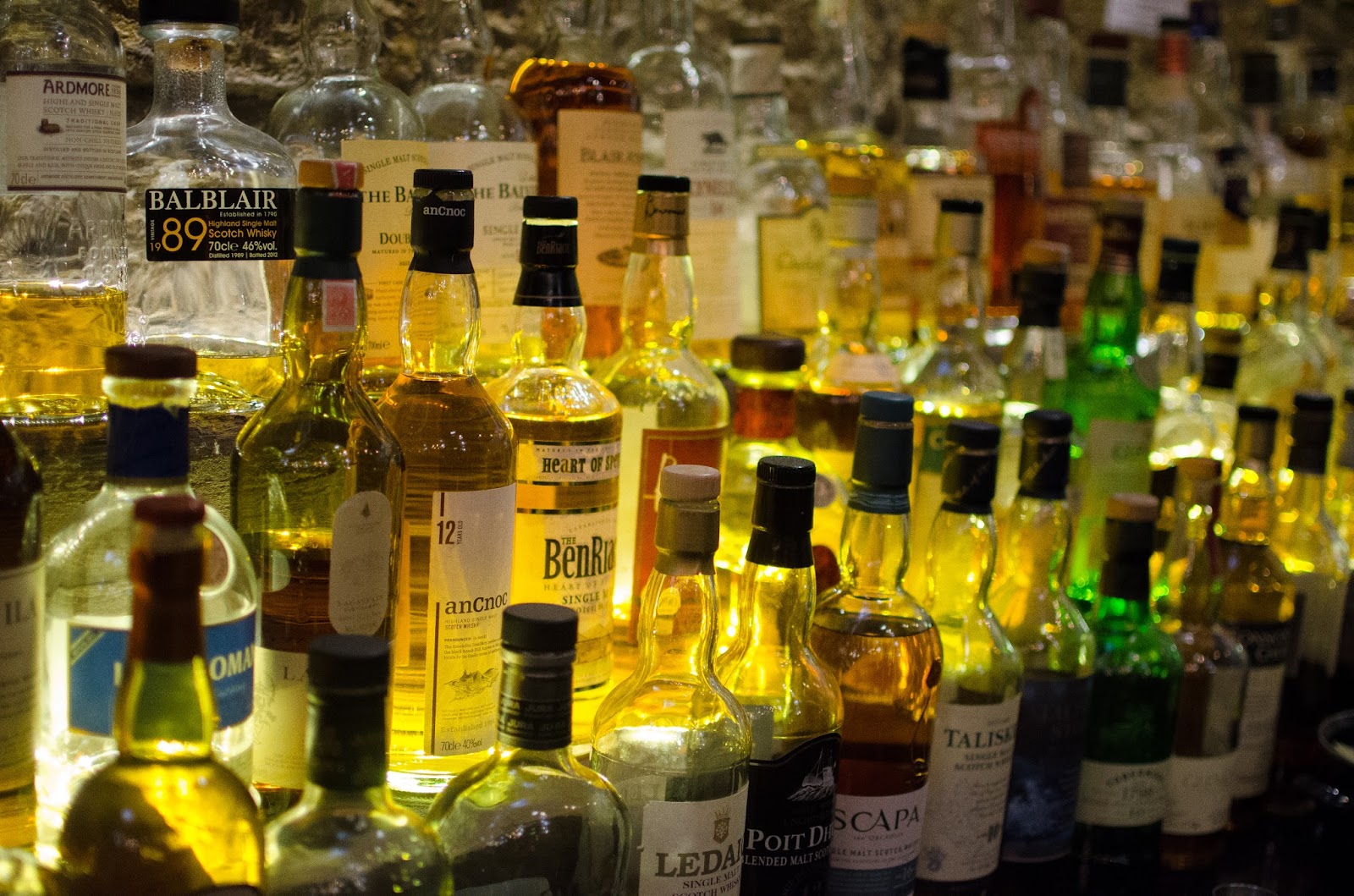 Rows of single malt whisky bottles lit from behind on the shelves at Teuchters.