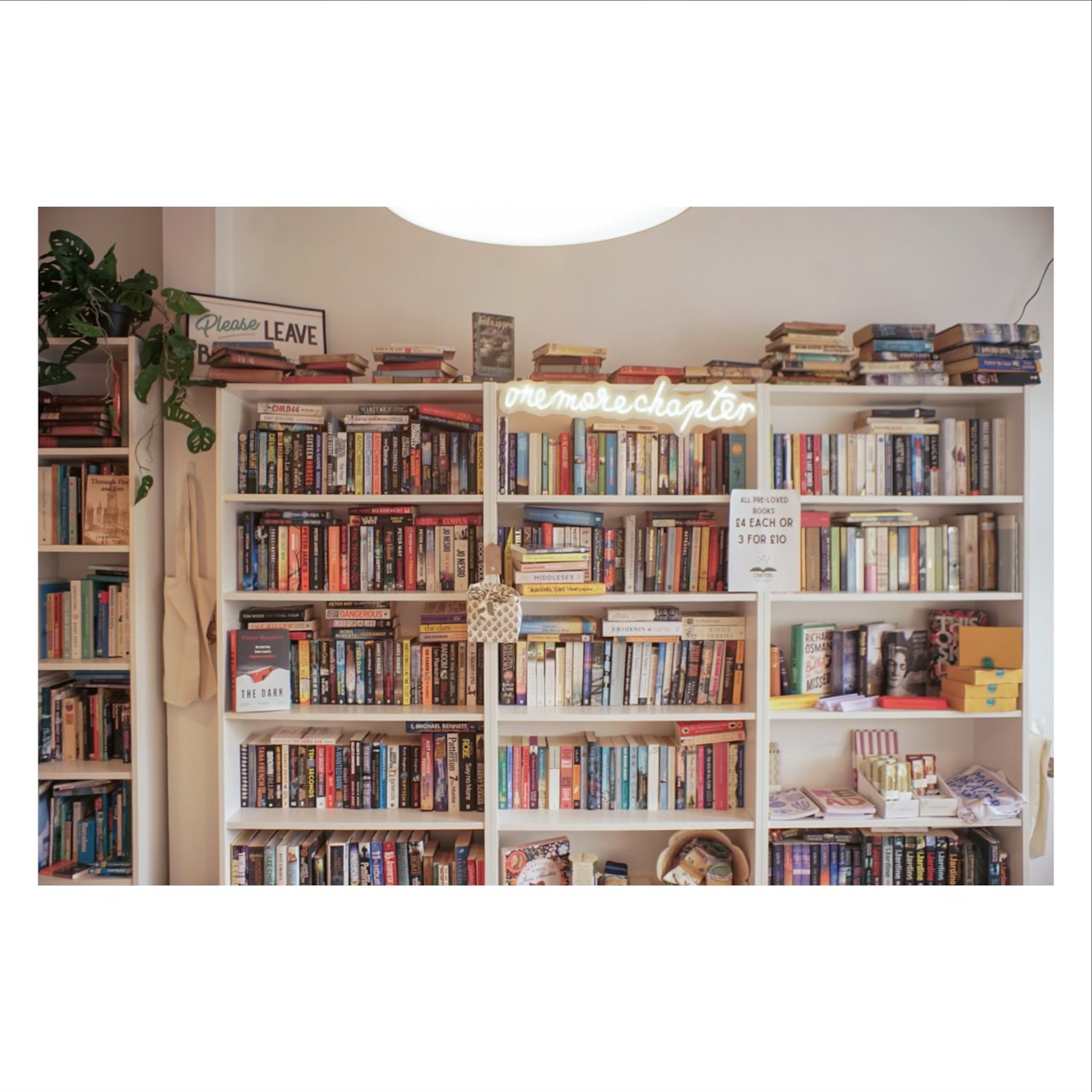 Bookshelves with a "one more chapter" neon sign and pre-loved books priced £4 each