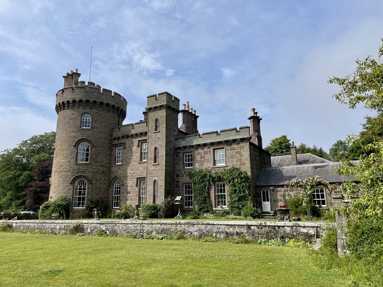 Dunninald Castle, its turrets and pinnacles above a green lawn.