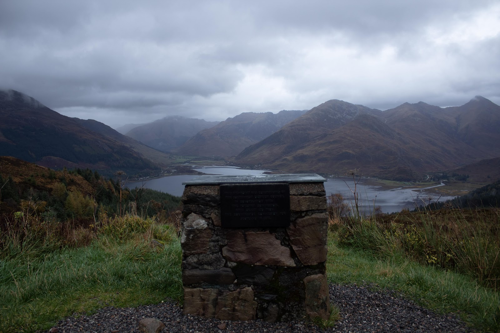 The stone cairn at the Ratagan Pass viewpoint, the Five Sisters of Kintail rising above Loch Duich beyond.